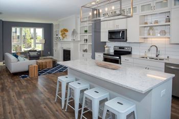 A modern kitchen with a white island and bar stools.